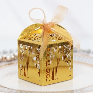 Golden laser-cut hollow wedding favor box with glitter finish and champagne silk ribbon