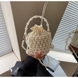 Detailed close-up of woven pearl bucket bag with drawstring satin lining and elegant handle