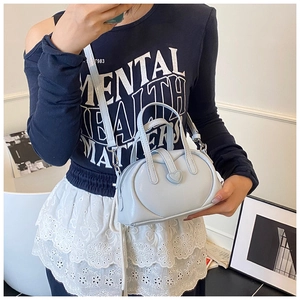 Close-up of light blue mini Boston bag featuring 3D heart cutout and metallic finish