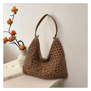 Detail of hand-woven hobo bag texture with a brown faux leather shoulder strap