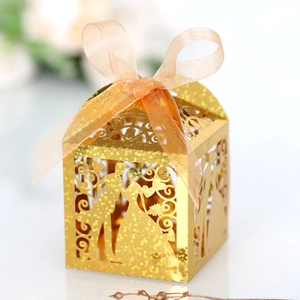 Detail of laser-cut gold wedding favor box with glitter finish and orange organza ribbon