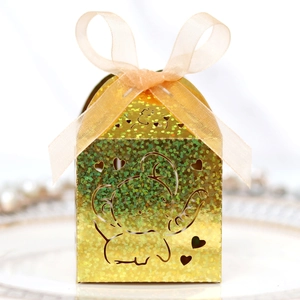 Detail of laser-cut glitter gold candy box with elephant pattern and champagne ribbon bow