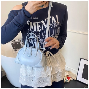 Detailed view of light blue dumpling bag with heart ornament shown on model