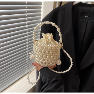 Detailed view of white pearl woven bucket bag with silk drawstring lining and beaded handle