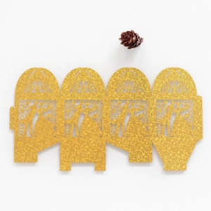 Detail of glitter gold laser-cut favor box with romantic silhouette and vine pattern
