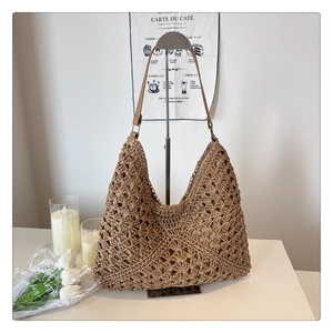 Detail of hollow crochet knit texture and leather strap on a beige woven tote bag