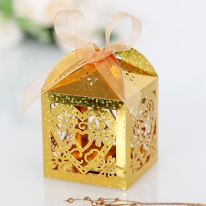 Detail view of a laser-cut gold heart favor box with intricate patterns and ribbon bow