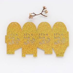 Detail of laser cut gold glitter candy box with It's a boy text and baby stroller pattern