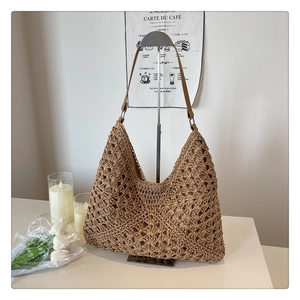 Detail shot of hand-woven straw hobo bag with high-quality brown leather shoulder strap