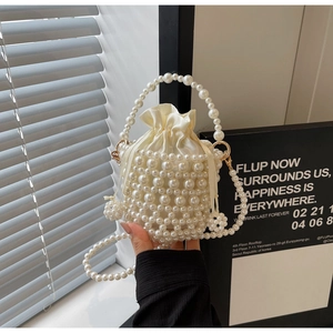 Close-up of handmade pearl woven bucket bag with satin drawstring liner and gold hardware