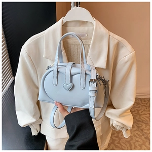 Detail of light blue leather handbag featuring a heart-shaped buckle and top handle