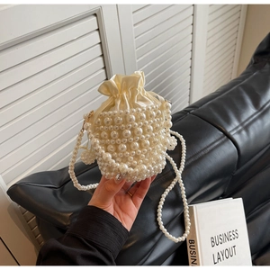 Detail of elegant woven pearl bucket bag with satin drawstring liner and shoulder strap