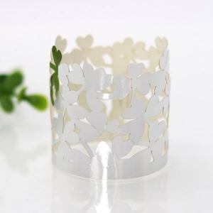 Macro shot of white pearlescent paper napkin ring with laser-cut clover patterns