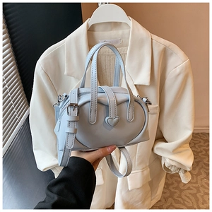 Detailed view of light blue heart-shaped handbag with adjustable strap and top handles