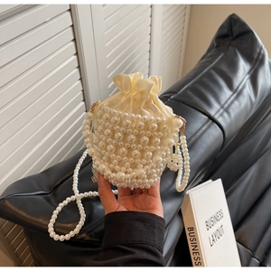Detailed close-up of handmade pearl woven bucket bag with satin drawstring pouch interior