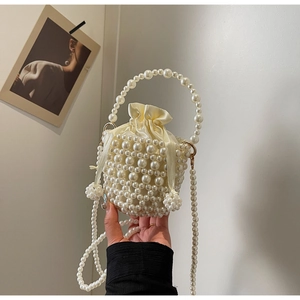 Detail of beaded pearl bucket bag with woven structure and satin drawstring closure