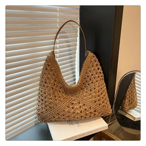 Detail of hand-woven hollow straw tote bag with brown leather strap in sunlight