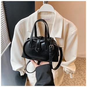 Close-up of black glossy pillow bag with heart detail and adjustable shoulder strap