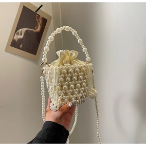 Close-up of woven pearl bucket bag with ivory satin drawstring liner and bead handle