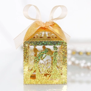 Detailed laser-cut gold wedding favor box featuring romantic silhouettes and ribbon