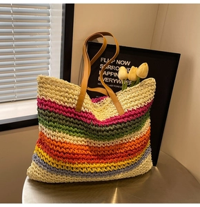 Detail of colorful rainbow striped woven straw tote bag with brown faux leather shoulder straps