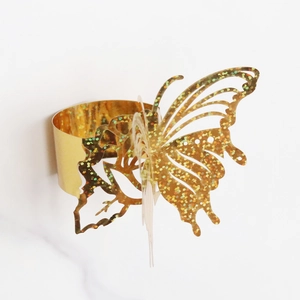 Macro shot of gold laser-cut butterfly napkin ring with glitter texture and mirror finish