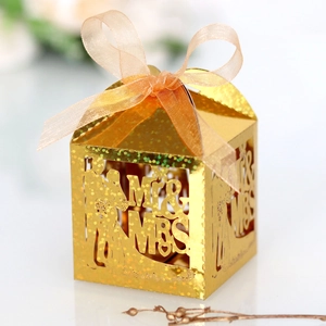 Macro shot of gold glitter laser-cut wedding favor box with Mr & Mrs silhouette design