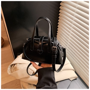 Detail of black leather handbag featuring a silver heart buckle and dual handles
