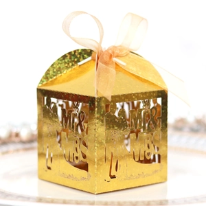 Macro detail of gold laser-cut Mr & Mrs wedding candy box with a champagne ribbon bow