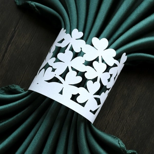 Macro shot of laser-cut clover pattern white napkin ring with green satin fabric detail