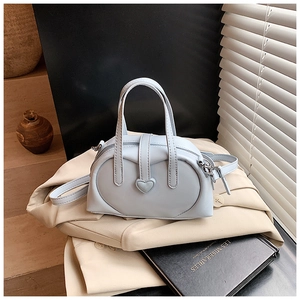 Detail of light blue pillow handbag with heart buckle on a beige blazer background