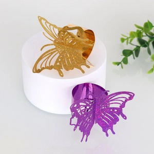 Detailed macro view of laser-cut butterfly napkin rings in gold and purple metal