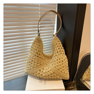 Detail of hand-woven straw tote with hollow-out pattern and brown leather strap