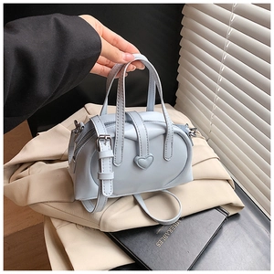 Detail of light blue leather pillow bag showing heart stitching and dual handles