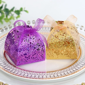 Détail de motifs de roses découpés au laser sur des boîtes de mariage dorées et mauves