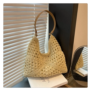 Detail view of beige woven tote bag featuring hollow knit pattern and brown leather strap