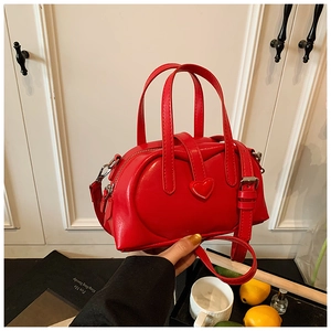 Detail of a bright red heart-shaped bag featuring glossy finish and metallic silver buckle