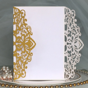 Detailed laser cut floral wedding invitation with gold glitter finish on elegant ceramic plate