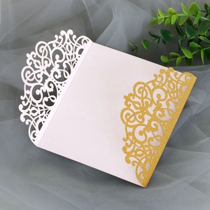 Detail of white laser-cut invitation with golden glitter accent and elegant scroll patterns