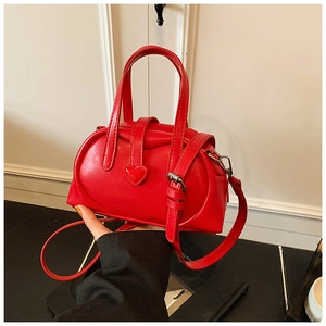 Close-up of a glossy red cylinder bag with a 3D heart detail and silver metal hardware