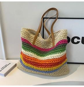 Detail of multi-color rainbow striped woven straw tote bag with brown leather handles
