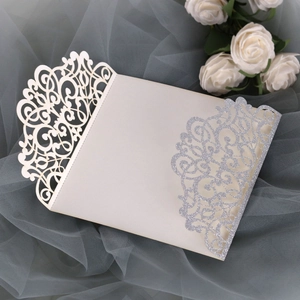 Detail of laser cut wedding invitation with cream paper and silver glitter floral pattern