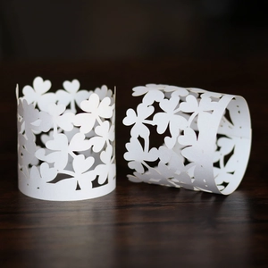 Macro detail of white pearlescent paper napkin rings with laser-cut clover pattern