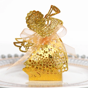 Detail of laser-cut golden angel candy box with intricate floral patterns and pink ribbon