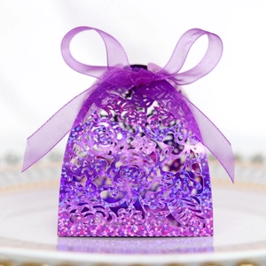Vue de boîte à bonbons rose découpée au laser violet avec ruban sur assiette à bord doré