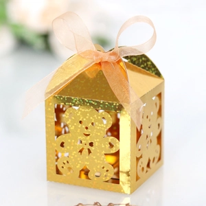 Macro detail of golden hollow bear gift box with orange ribbon bow and glitter finish