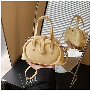 Detail of butter yellow Boston bag featuring heart-shaped buckle and dual handles