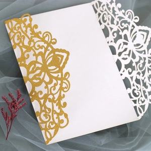 Macro detail of laser-cut wedding invitation with gold glitter floral hollow patterns