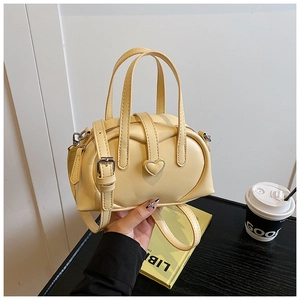 Detail view of the yellow Boston bag with heart buckle and detachable shoulder strap