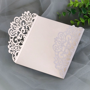 Detail showing laser-cut floral pattern and silver glitter on cream wedding invitation